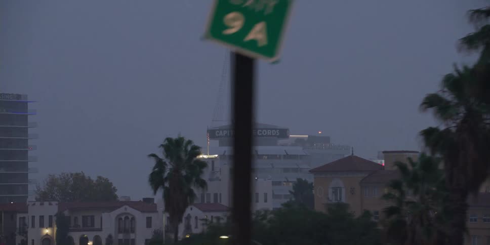 Traffic signs mark the side of a highway running past downtown