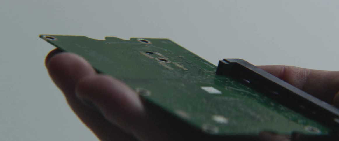 A man examines a circuit board that he holds in his hands