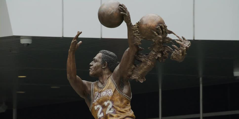 Dynamic statue of basketball player stands near building