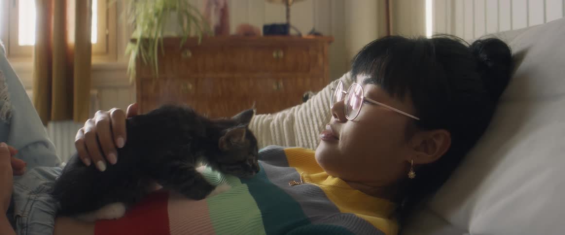 A woman is laying down and petting her cat