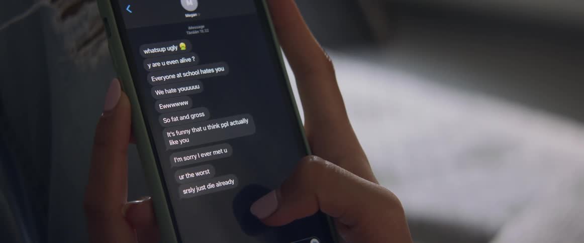 Female holding a cell phone with bullying text messages on screen