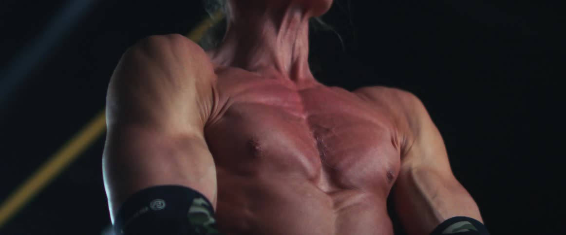 A mans veins pop as he lifts weights in a gym