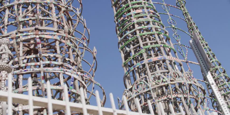 Passing by ornate metal towers located behind a metal fence in a park area in the daytime