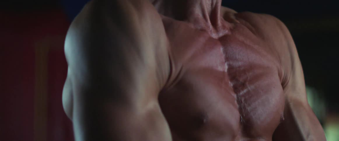A man flexes his muscles as he lifts weights