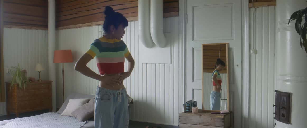 A woman sucks in her stomach as she examines her body in the mirror