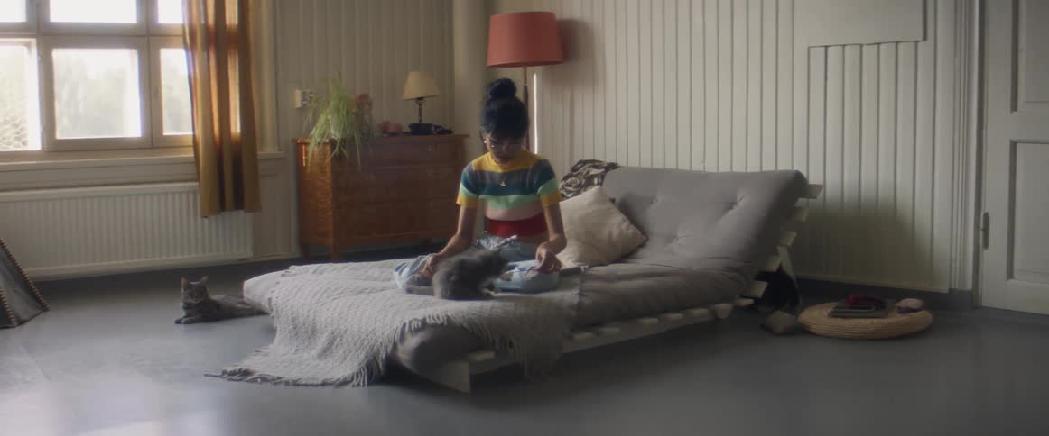 A girl is playing with a kitten in bed