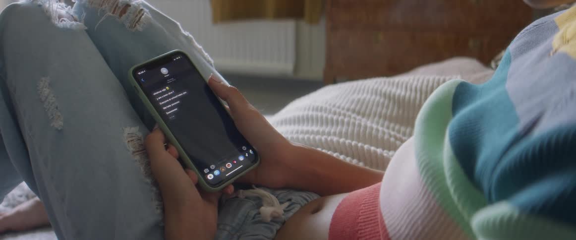 A woman reads text messages as she lies back with her phone