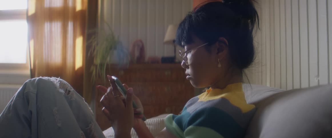 A woman is sitting on a couch and looking at her cellphone
