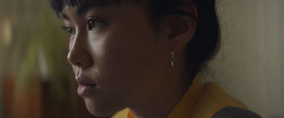 Asian woman wearing an earring looks deep in thought