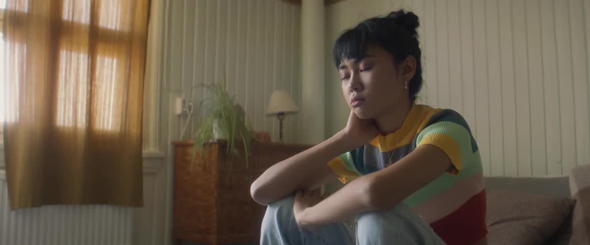 A girl sits looking depressed in her room