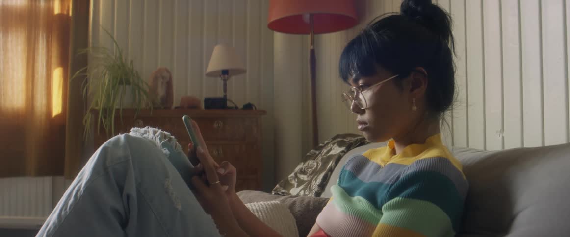 A woman is sitting on a couch and looking at her cellphone