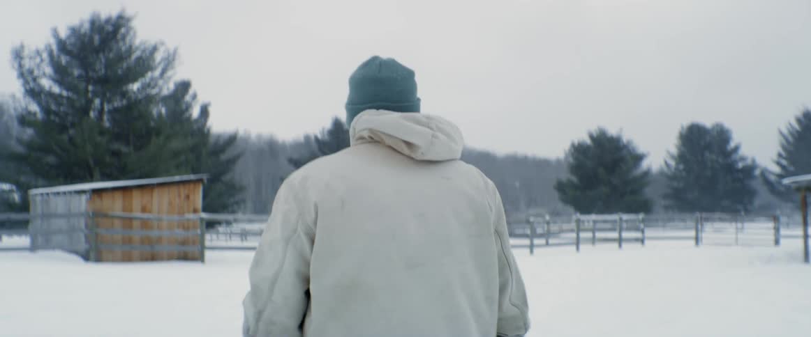 A man is walking in the snow on the ranch