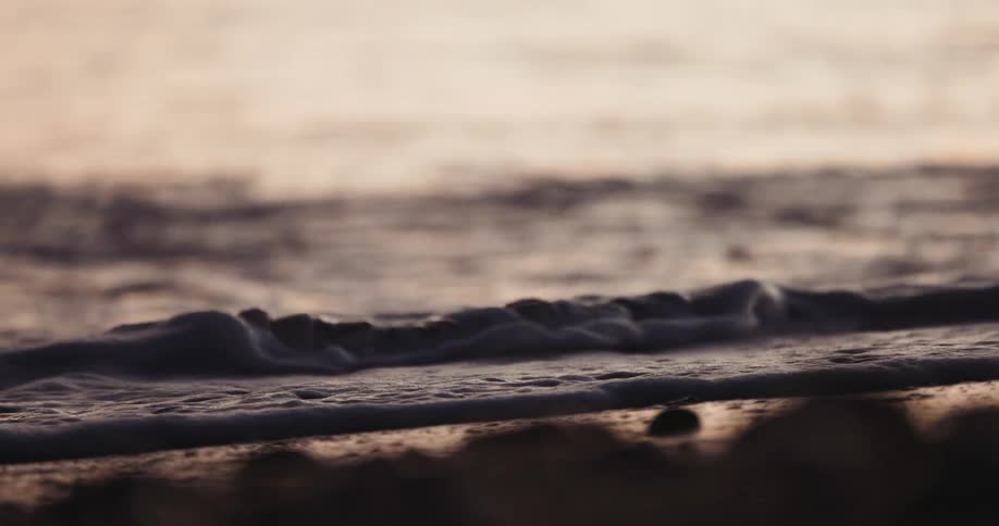 Waves are rolling into shore as the sunlight reflects on the water