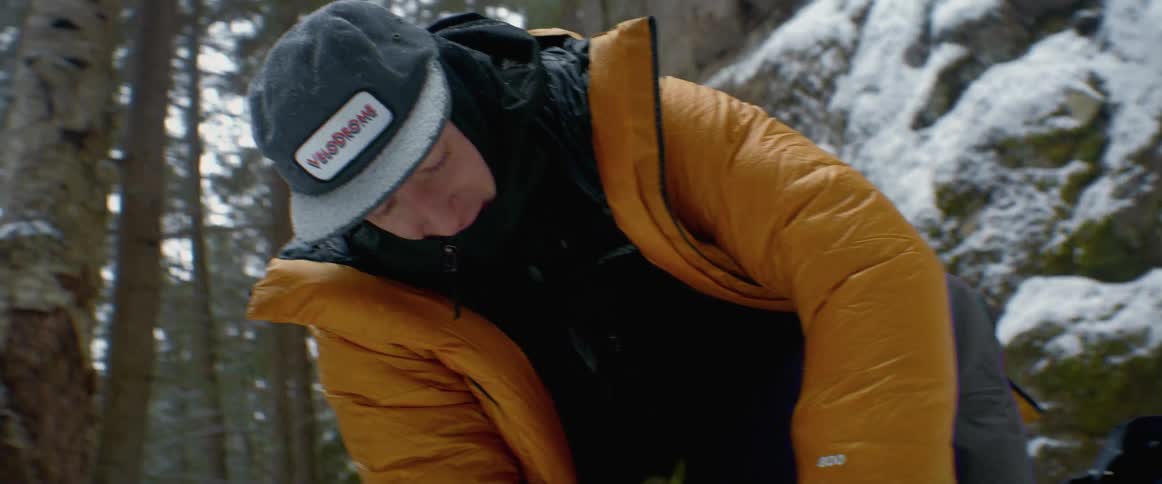 A man is tying his boots in the snow