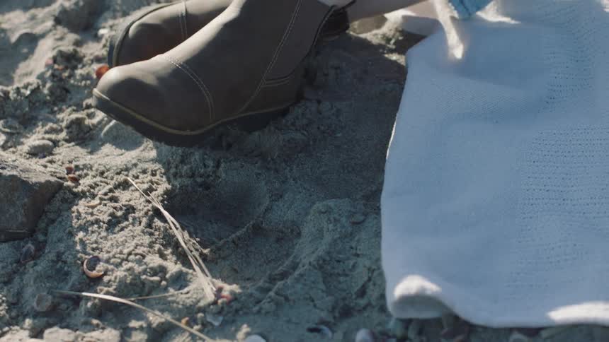 A woman sits on a towel on the beach