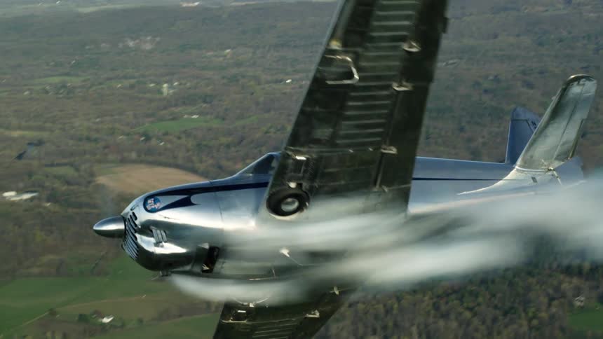 A man is flying a small airplane over a forest and the airplane is smoking as it turns