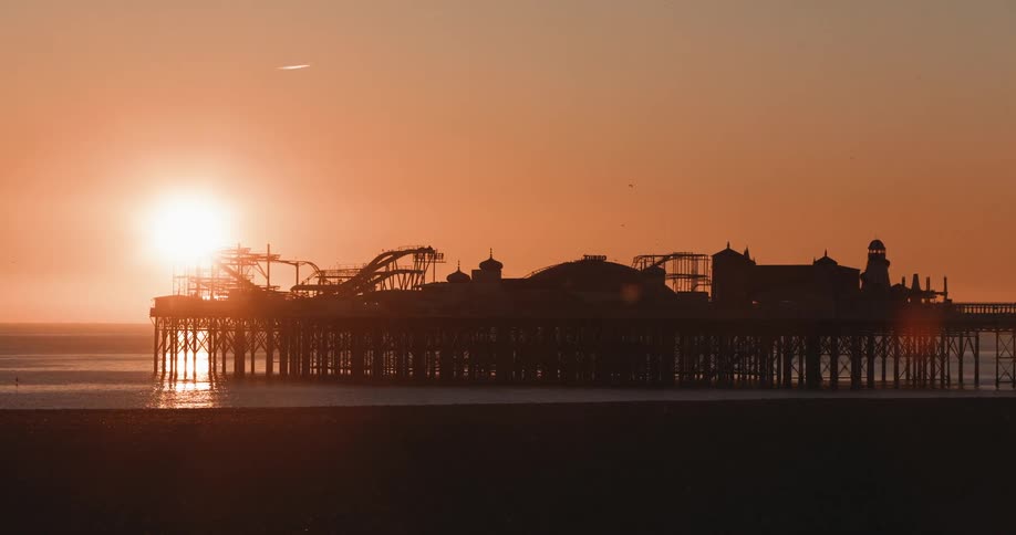 An amusement park located on a pier on a beach at sunset