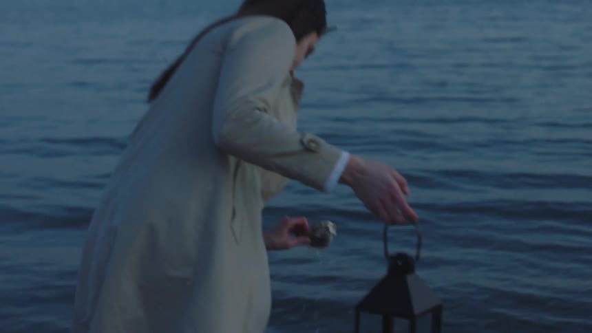 A woman picks up a rock and throws it in the water
