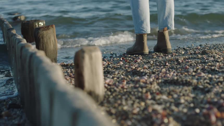 Woman wearing boots and jeans jumping on the beach low tides