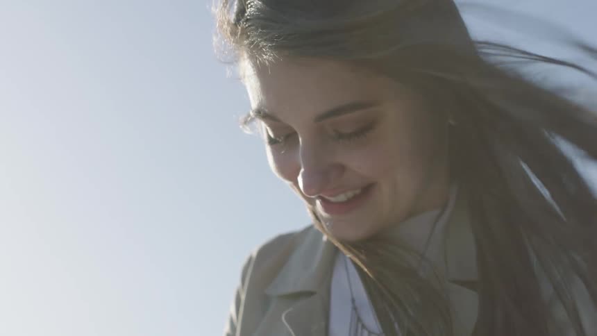 Closeup of happy woman with wind blown hair looking down