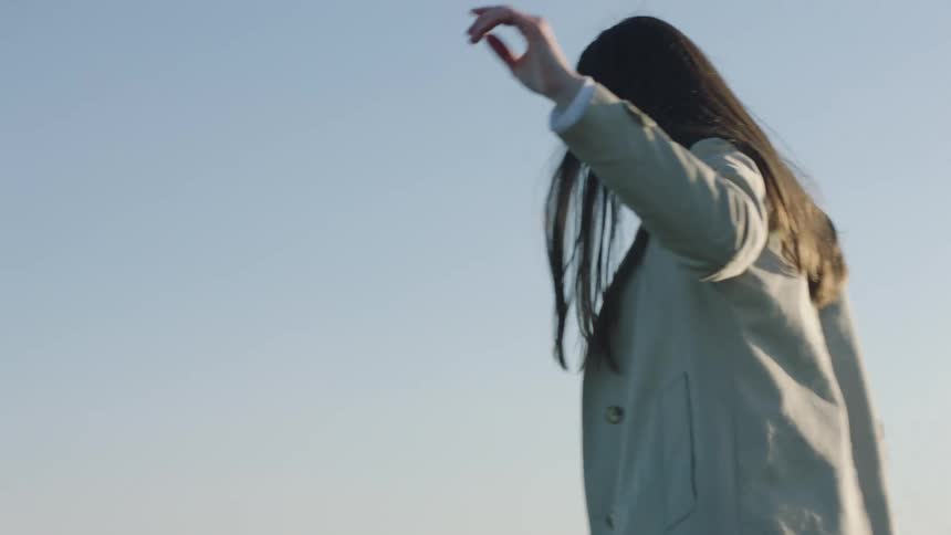 A young woman walks along a ledge on the beach like a balance beam