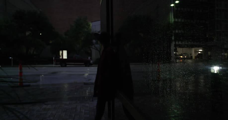 A woman in a hat stands in a darkened area