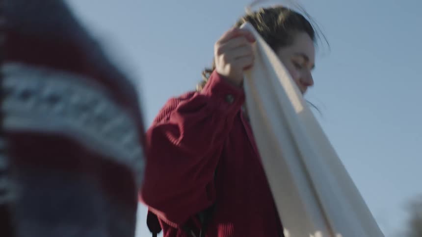 Two women talk outside as they shake out and fold blankets