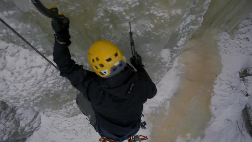 A woman climbs up the side of a snow covered canyon