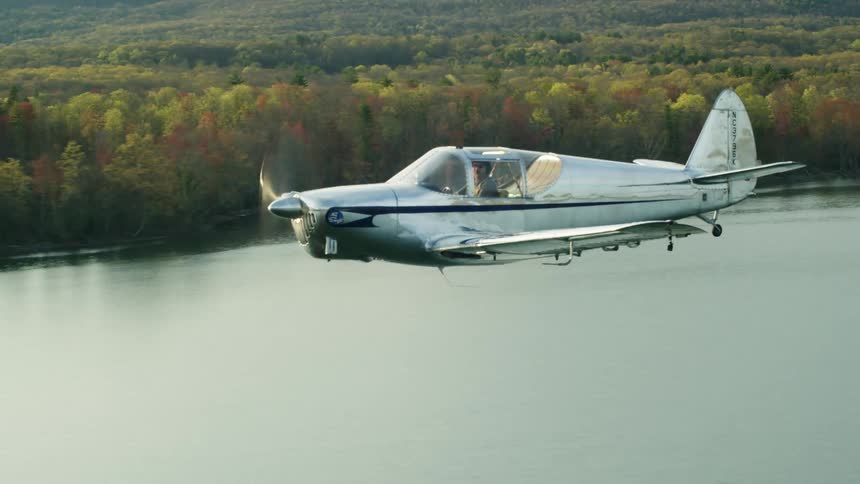 A man flying a small plane over a lake