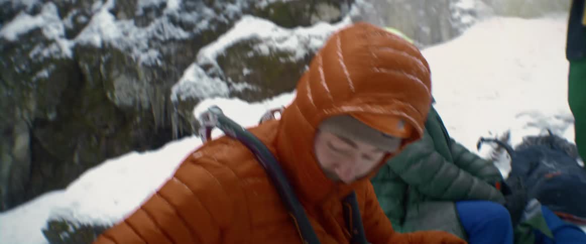 Mountain climbers gather equipment near ice coated mountains side