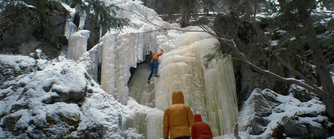 A person is climbing up the ice on the cliff
