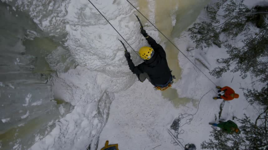 A man is climbing up the cliff with gear