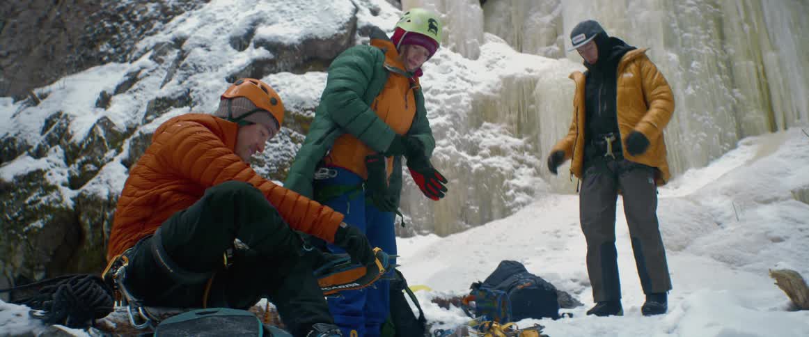 A group of men get their climbing gear ready in front of an ice covered mountain
