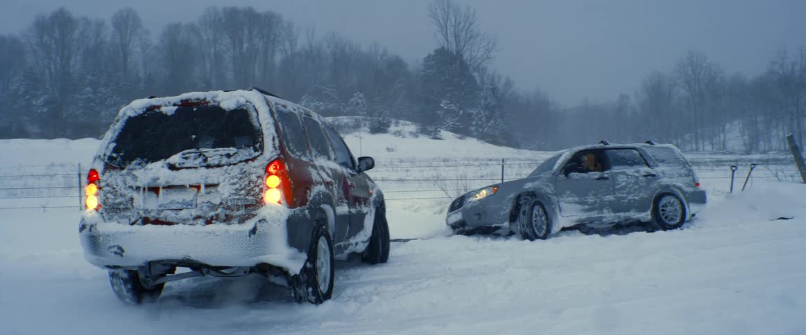 A car pulls a stuck car out of the snow