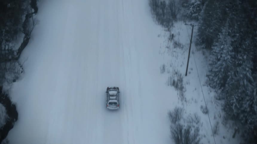 A vehicle drives over a snow covered rural road