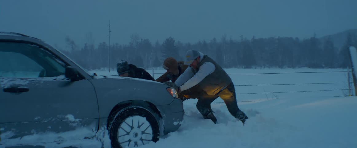 Three men rest after trying to push a car stuck in the snow