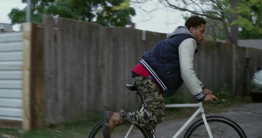 A man rides his bike up a sidewalk to a gate