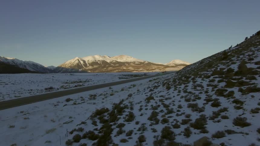 Road surrounded by snow covered hills and mountains