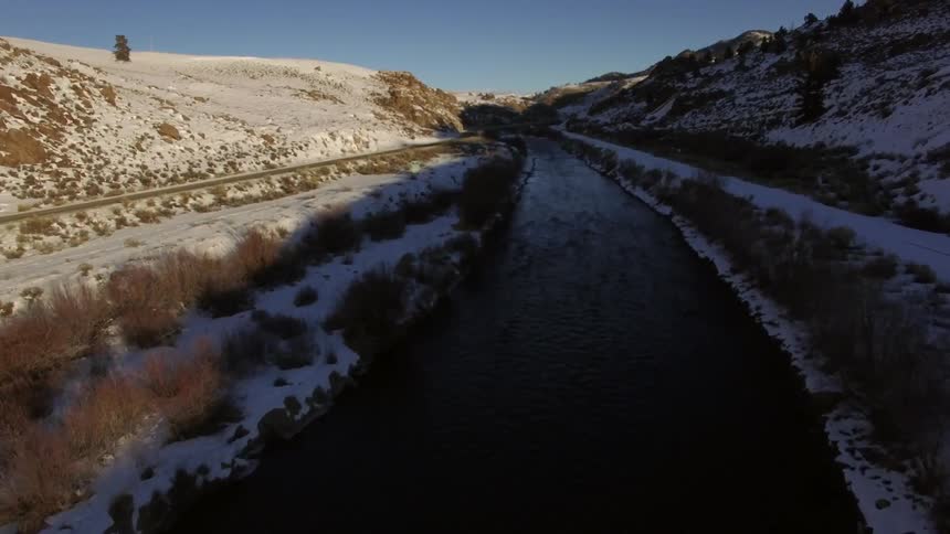 A river next to a snowy road on a clear day