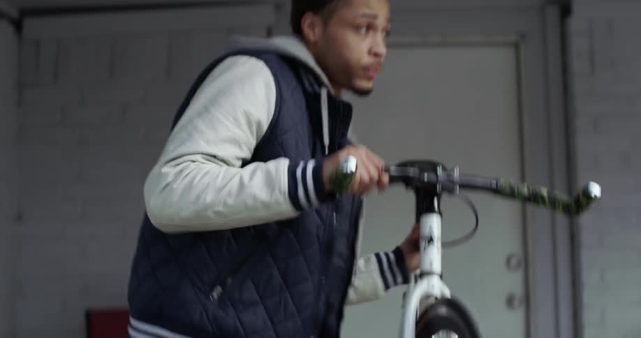 A young man lifts a bicycle up and carries it