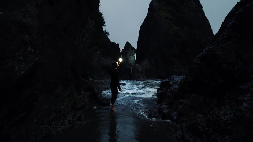 A woman searches at sunset by the cove on the beach