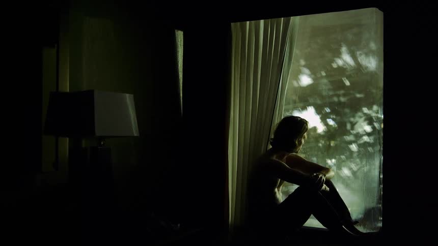 A man sits on the window looking outside