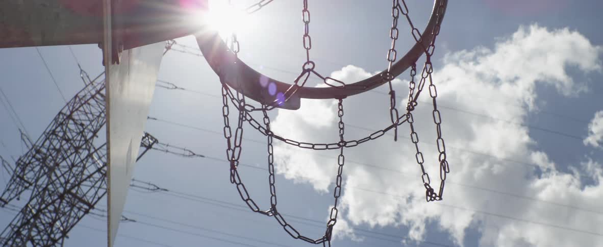 A rusty net made of chains hangs from a basketball backboard