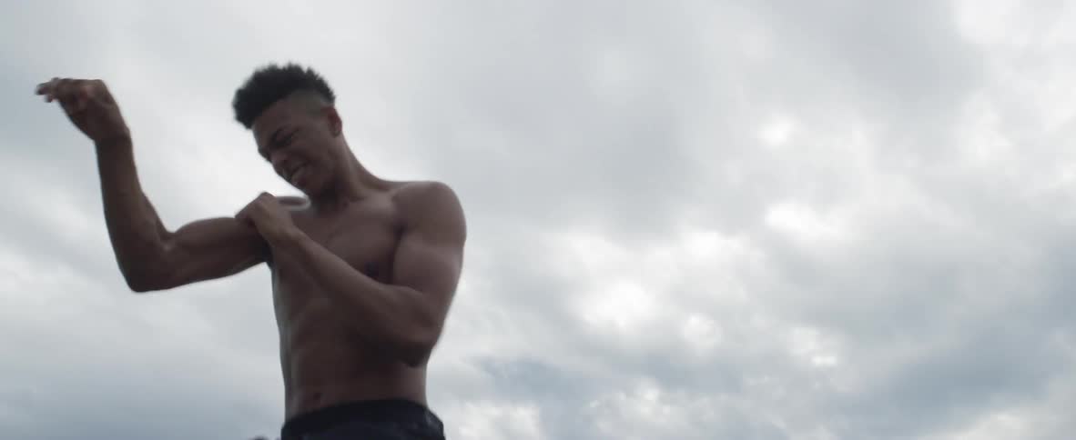 A teenage boy throws punches as he boxes outside