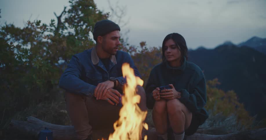 Couple relaxing in front of bonfire in the wilderness