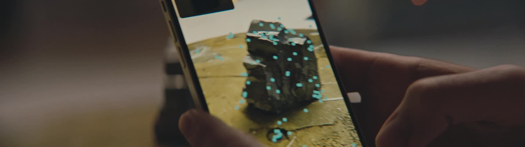 Hand holds a cell phone while using the phones camera to examine a piece of coal