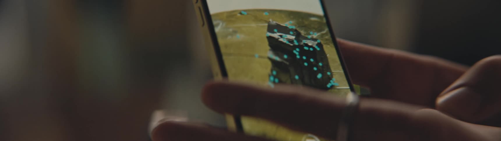 Hands holding a cell phone filming a sculpture and marking it for 3d rendering
