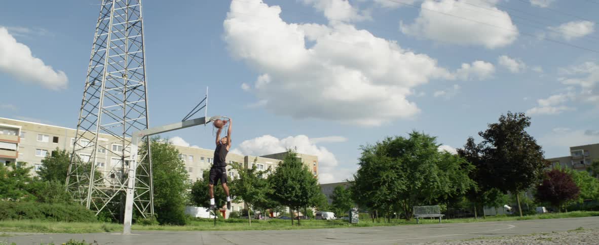 Young black man playing basketball alone at a public park and scoring a point