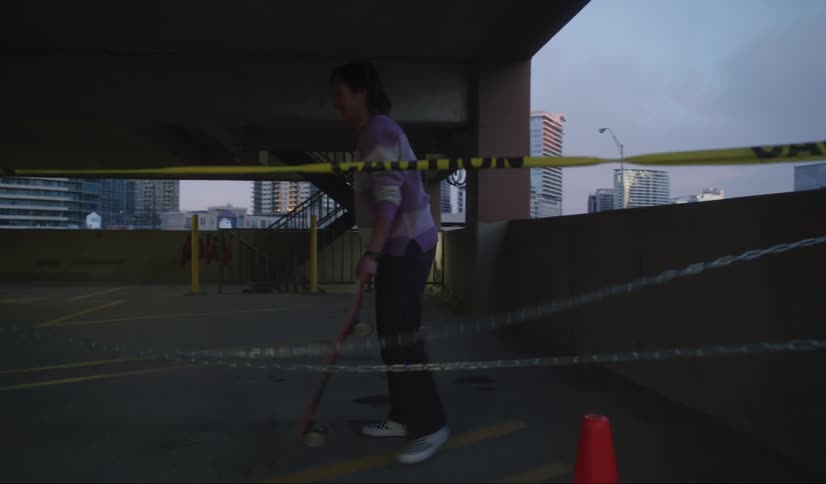 Two teenagers cross under yellow caution tape to ride their skateboards in a restricted area of a parking garage