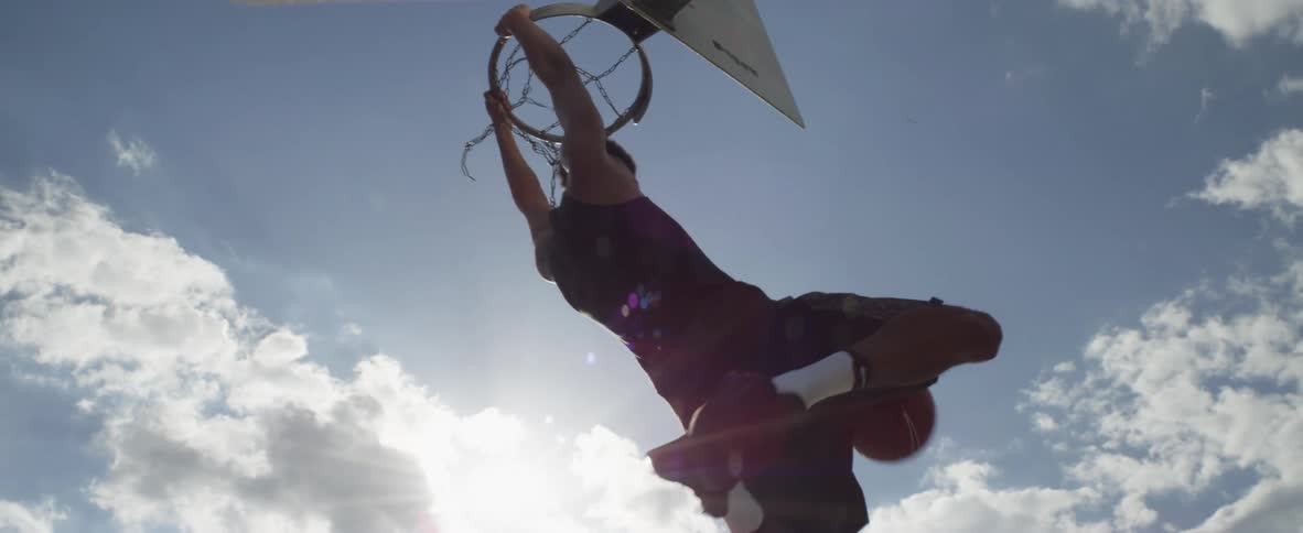 Black young man wearing athletic clothing playing basketball jumping and scoring a point